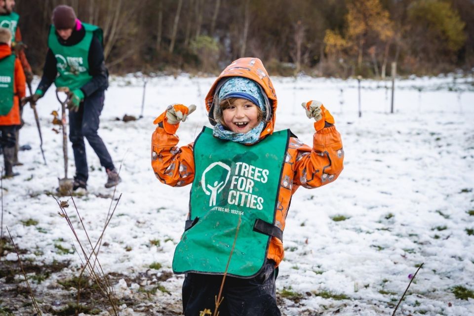 A young Trees for Cities volunteer planting young trees in the snow