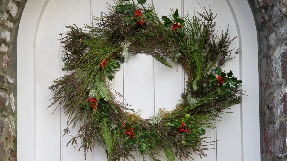 a wreath on a door with holly in it